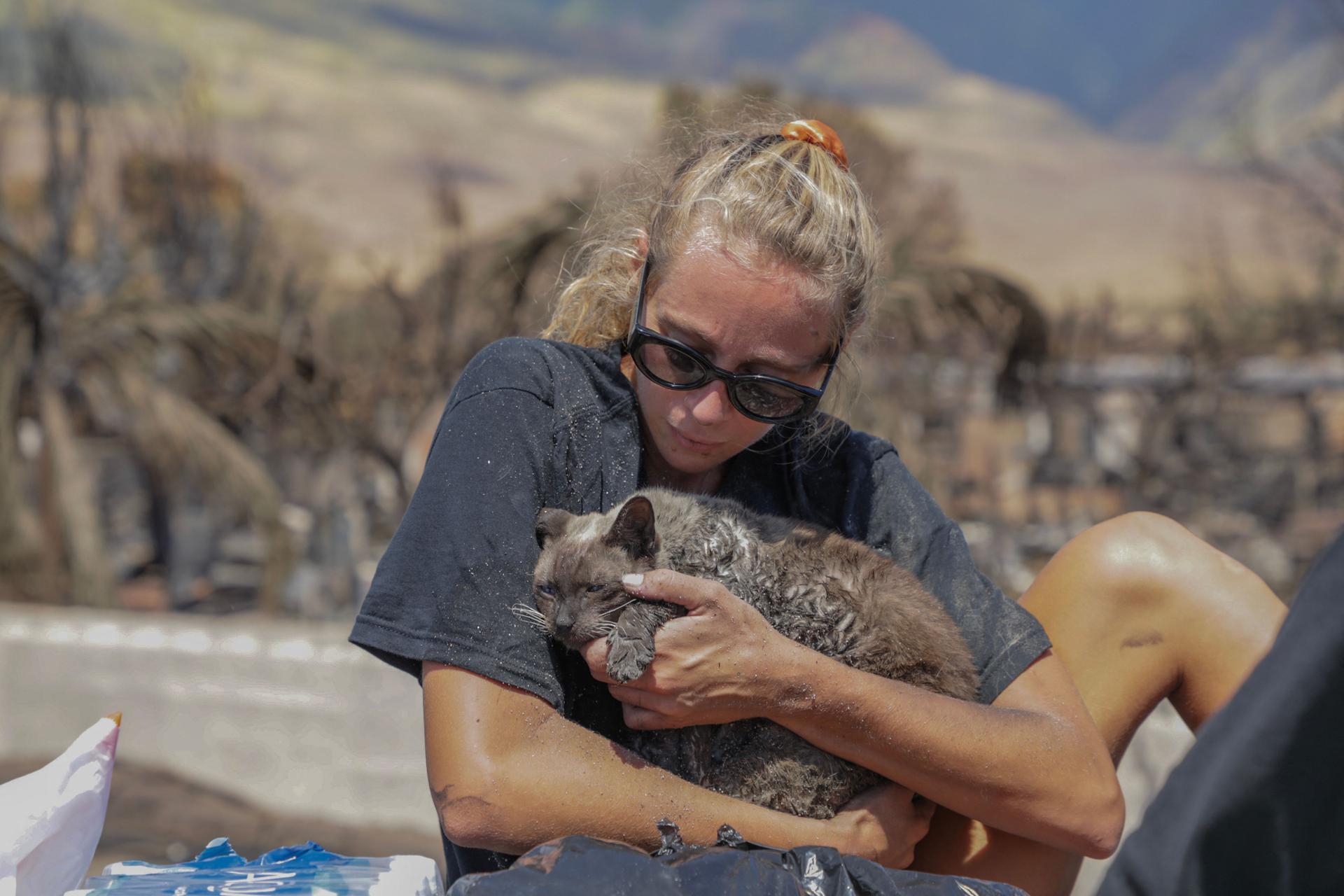 A woman cradles her cat after finding it in the rubble of the fire in the town of Lahaina, West Maui, Hawaii, August 11, 2023.