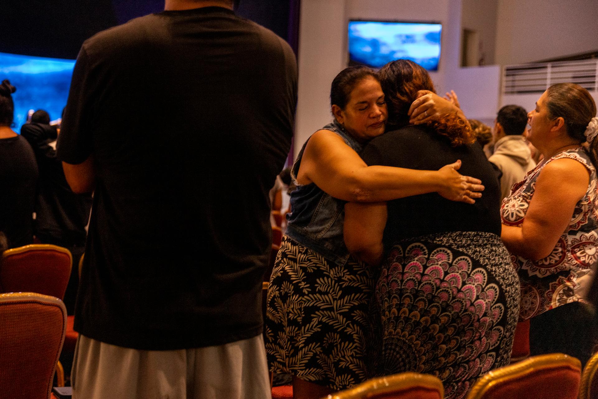 Participants in a church service embrace at King's Cathedral in Kahului, on the island of Maui, Hawaii, Sunday, August 13, 2023. The church has been transformed into an emergency shelter.