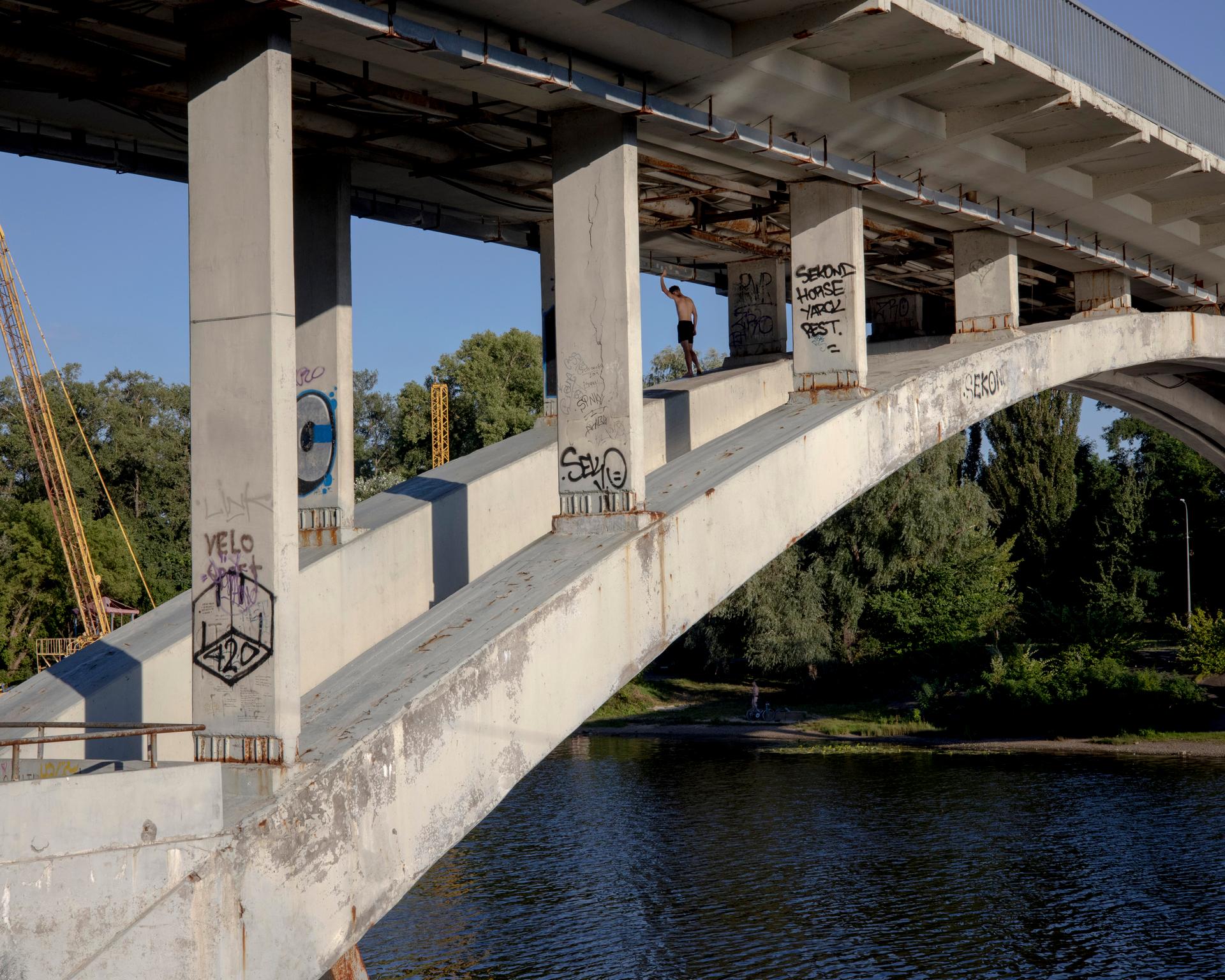 A Ukrainian man stands under a bridge on Hydropark Island, in Kyiv, on August 13, 2023.