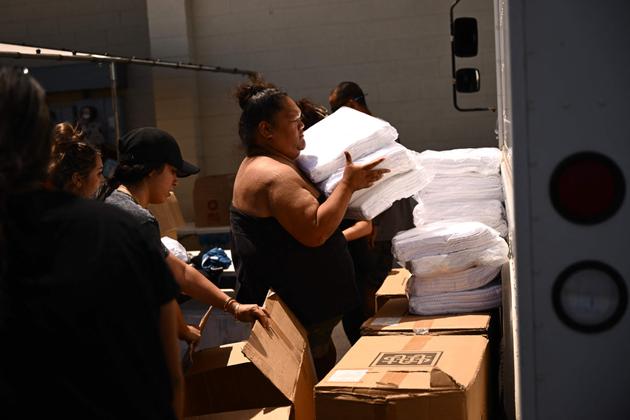 Volunteers carry supplies for distribution to victims fo the wildfires in West Maui in Wailuku, Hawaii, August 12, 2023.