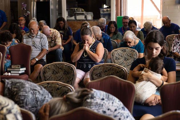 Survivors and worshippers pray during a Sunday service organized by Pastor Brown of Grace Baptist Church in Lahaina, at the Maui Coffee Attic in Wailuku, central Maui, Hawaii, August 13, 2023.