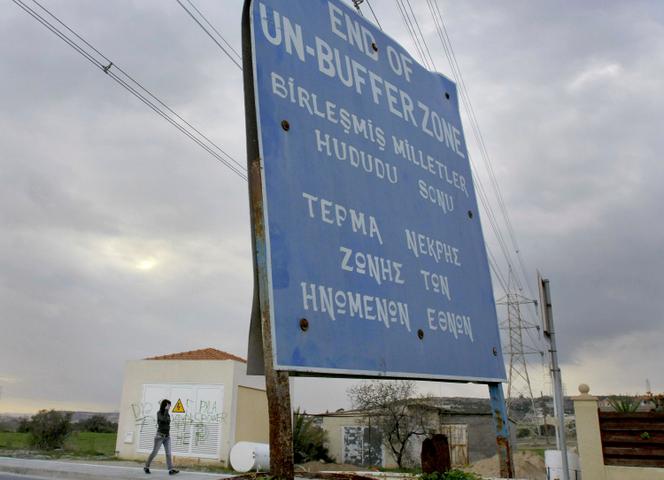 A woman walks by a UN sign at the UN buffer zone inside Pyla village, outskirt of coastal city of Larnaca, Cyprus, Thursday, Jan. 8, 2009.
