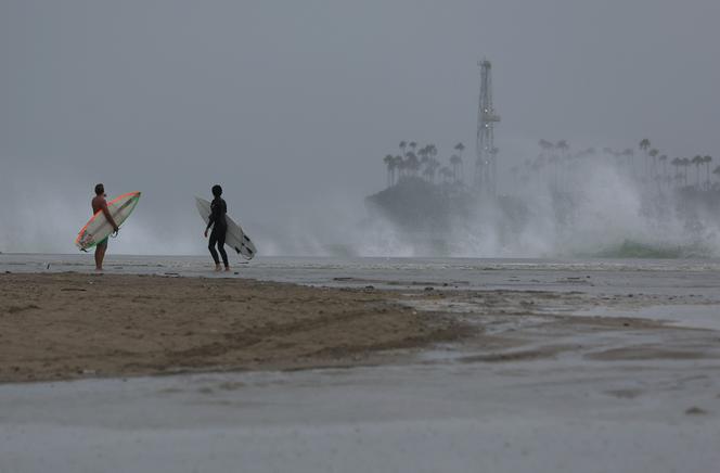 Surfers look at crashing waves at Belmont Shore Beach as tropical storm Hilary approaches on August 20, 2023, in Long Beach, California.