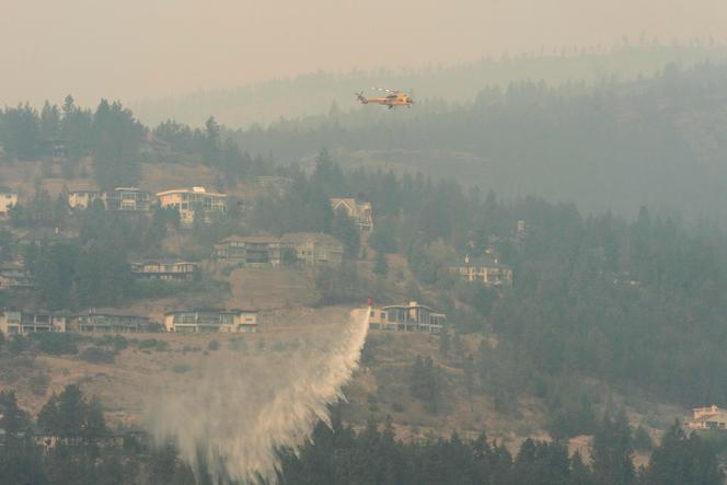 A helicopter drops water as the McDougall Creek wildfire continues to burn in West Kelowna, British Columbia, on August 19, 2023.