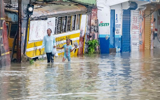 People walk through a street flooded by the rains of Tropical Storm Franklin in Santo Domingo, Dominican Republic on Tuesday, August 22, 2023. 