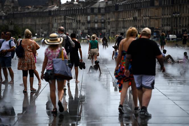 People cool down as they walk on a thin layer of water at the Mirroir d'Eau along the Garonne river in Bordeaux, southwestern France on August 23, 2023.