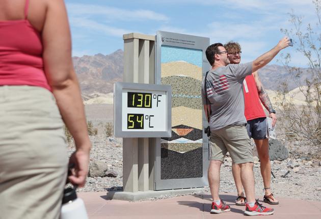 Tourists take a photo at the Furnace Creek entrance to Death Valley National Park in California on July 16, 2023.