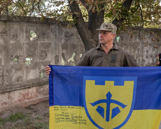 Serhiy Rudenko, a soldier returning from the Bakhmut front, carries a flag signed by his brothers-in-arms, in Irpin, Ukraine, on August 23, 2023, during National Flag Day celebrations.