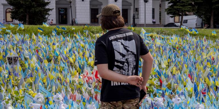 A Ukrainian man stands in front of several thousand flags, each representing a person killed in war, are planted on a lawn in Kiev's Maidan Square, during Flag Day celebrations on August 23, 2023.