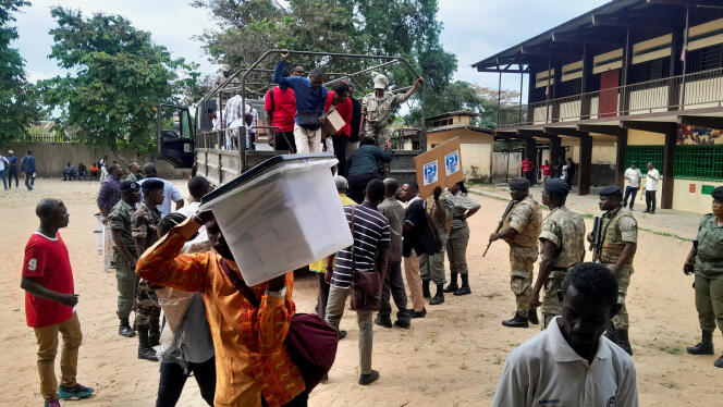 Los asesores transportan material electoral mientras los gaboneses esperan la apertura de su oficina electoral, en Libreville, el sábado 26 de agosto de 2023.