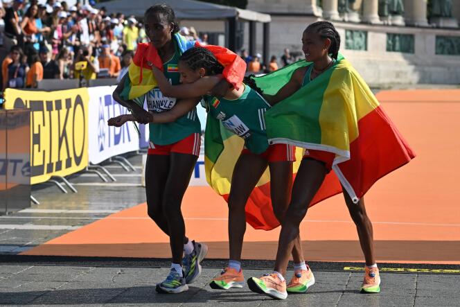 La medallista de oro etíope Amane Beriso Shankule (izquierda) y el medallista de plata Gotytom Gebreslase (derecha) ayudan a su compatriota Yalemzerf Yehualaw después del maratón femenino en el Campeonato Mundial de Atletismo en Budapest, el 26 de agosto de 2023. 