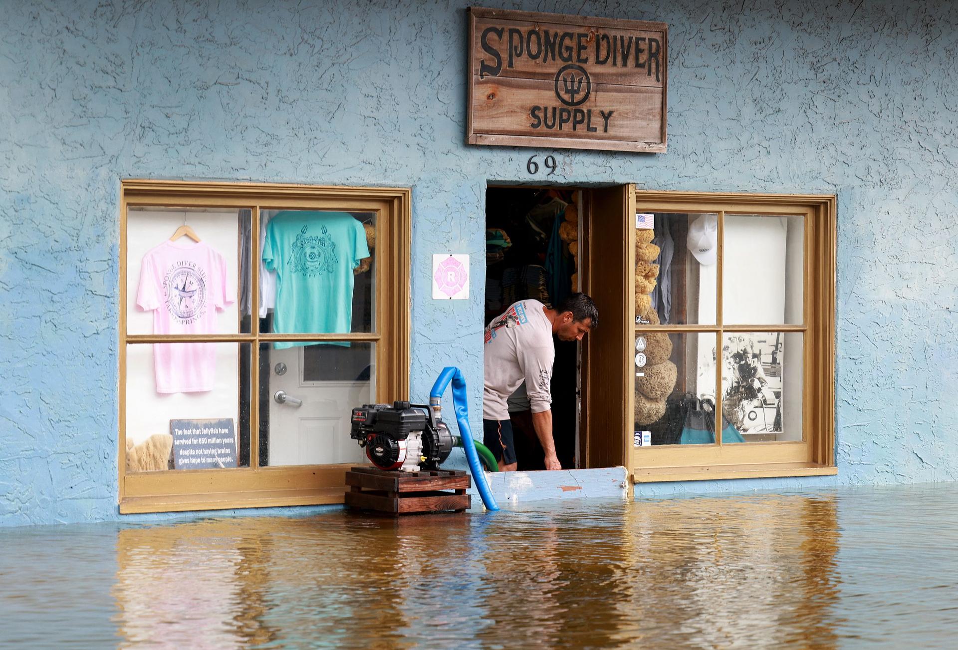At the entrance to a store in Tarpon Springs, Florida, a pump attempts to keep water out, on August 30, 2023.