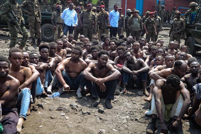 People arrested during a military operation to prevent a planned demonstration against the United Nations by a religious sect, sit on the ground and guarded by the army in Goma, eastern Democratic Republic of Congo on August 30, 2023. 