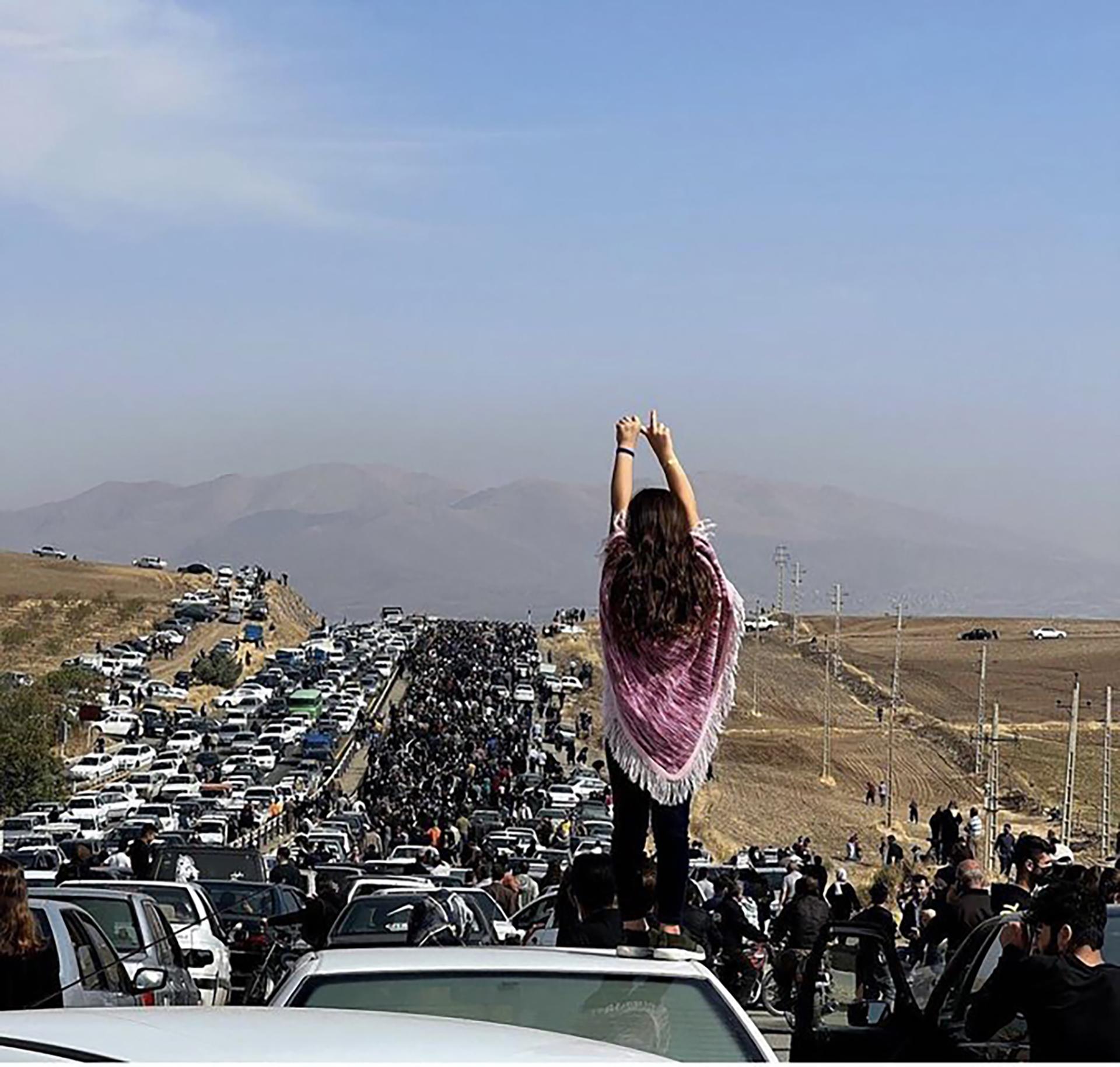 A young woman without a veil stands on a vehicle as thousands of people make their way to Aychi cemetery to commemorate the 40th day of Mahsa Amini's death, in Saqqez, her hometown. Saqqez, Iranian Kurdistan, October 26, 2022.
