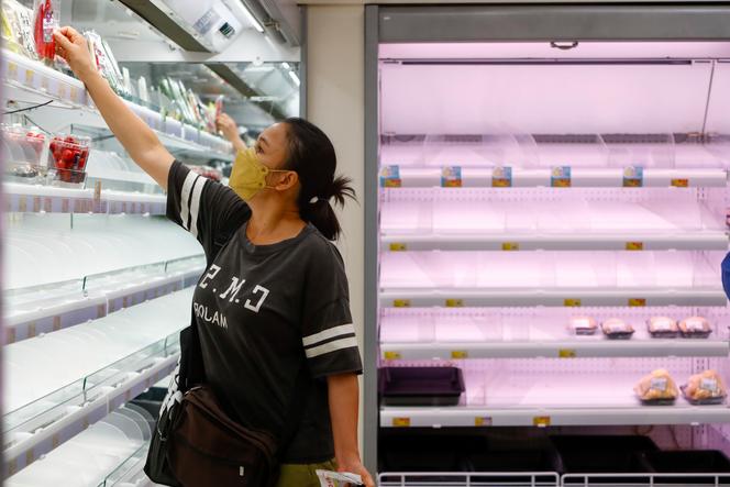 A woman selects products near-empty shelves at a supermarket as Super Typhoon Saola approaches Hong Kong on September 1, 2023. 