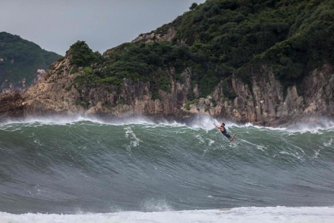 A surfer paddles over a wave generated by Typhoon Saola at a beach in Hong Kong on September 1, 2023.