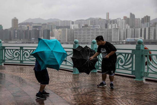 People struggle with their umbrellas in high winds brought by Super Typhoon Saola next to Victoria harbour in Hong Kong on September 1, 2023. 