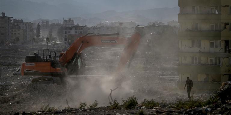 OZAN KOSE / AFP A man watches as diggers work to clean the rubble of collapsed buildings, five months after a 7.8-magnitude jolt and its aftershocks wiped out swathes of Turkey's mountainous southeast, in antakya on July 9, 2023. The excavator tore into the remnants of the damaged building in southeast Turkey, bringing them crashing down into a cloud of dust -- the latest menace facing survivors of the deadly February quake that ravaged the region. Extending to the horizon, a cocoon of fine grey dust envelops the city of Samandag, which was devastated by the February 6 earthquake that killed more than 55,000 people and lay waste to parts of Turkey and Syria. (Photo by OZAN KOSE / AFP)