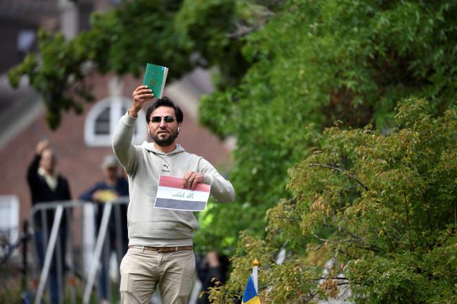 Protestor Salwan Momika holds up the Muslim holy book and a sheet of paper showing the flag of Iraq during a protest outside the Iraqi Embassy in Stockholm, Sweden, on July 20, 2023.