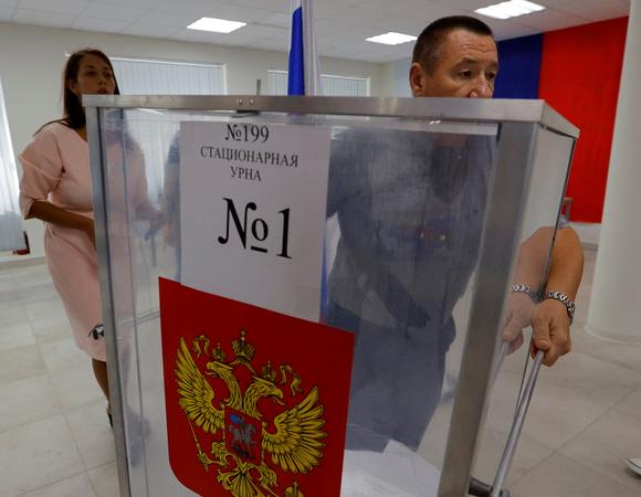 Un membre de la commission électorale transporte une urne, dans un bureau de vote à Donetsk, dimanche 10 septembre 2023.