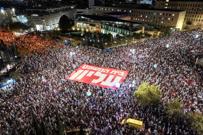 Una vista aérea muestra a miles de personas sosteniendo una pancarta en hebreo que significa 