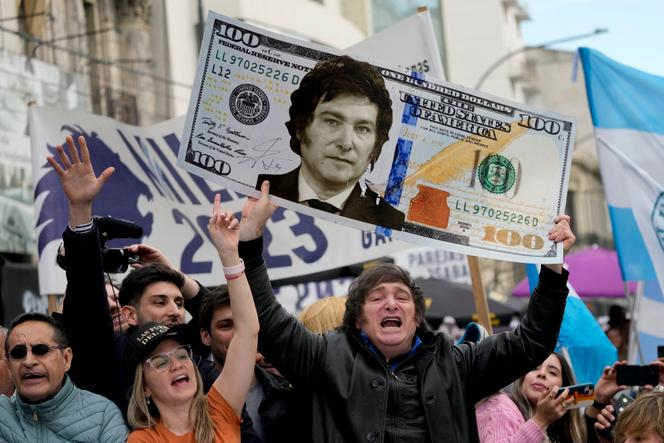 Ultra-liberal candidate Javier Milei holds up a sign bearing his image on a $100 bill at a rally in La Plata (Argentina), September 12, 2023.
