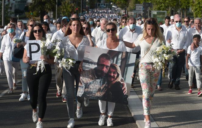 Philippe Monguillot's wife, Véronique Monguillot (center), holds a photo of her and her husband during a white march in tribute to the bus driver attacked, in Bayonne (Pyrénées-Atlantiques) on July 5, 2020 and died five days later.