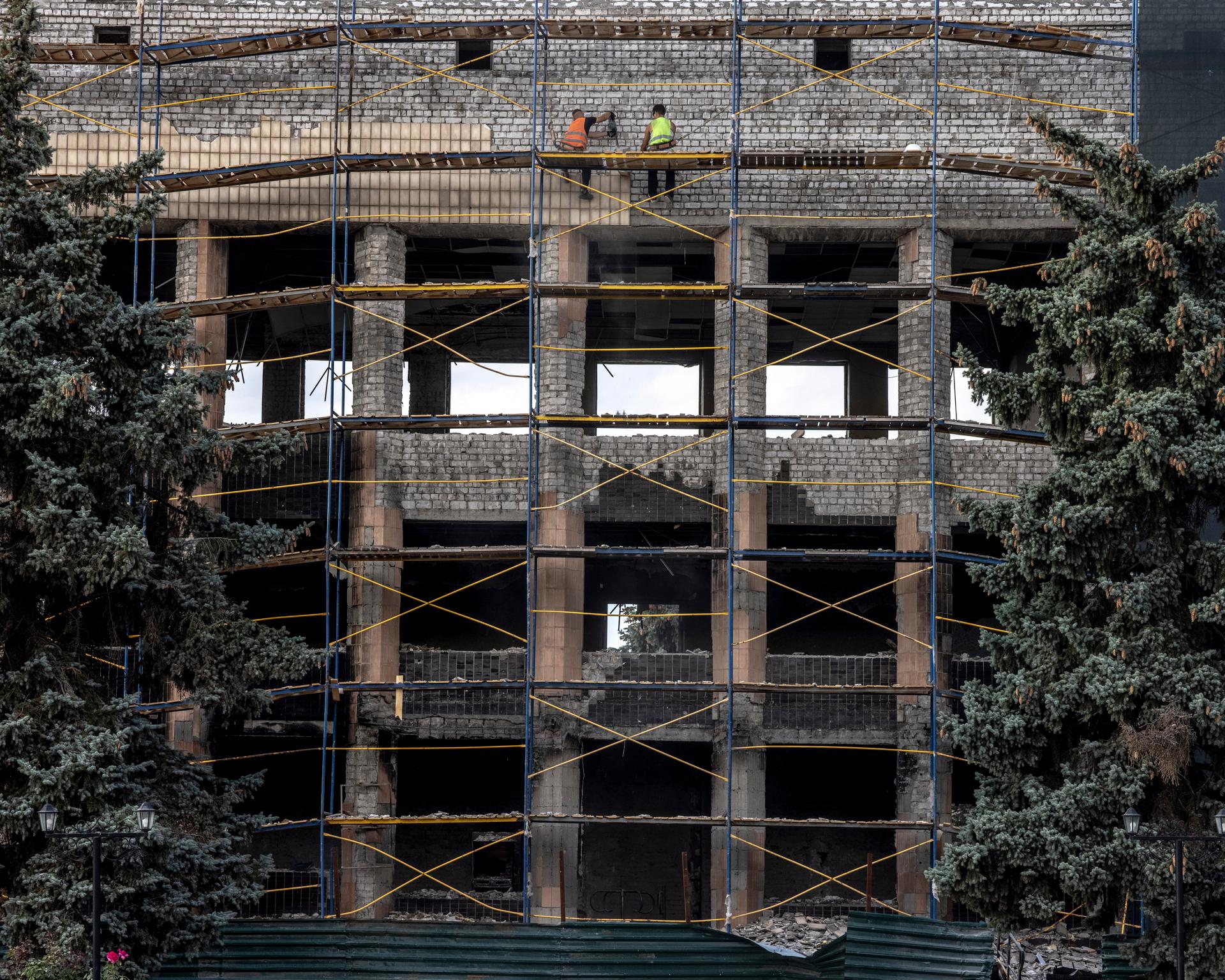 Des ouvriers ukrainiens rénovent le bâtiment administratif détruit par l’armée russe, dans le centre -ville d’Izioum (Ukraine), le 12 septembre 2023. 