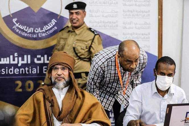 A photo posted by the Libyan High National Commission Facebook page on November 14, 2021 shows Saif Al-Islam Gaddafi (left), registering to run in the December presidential elections, in southern Libya, Sebha.