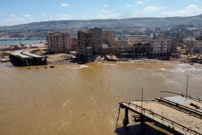 An aerial view shows a destroyed bridge in Libya's eastern city of Derna on September 19, 2023, following deadly flash floods. A week after a tsunami-sized flash flood devastated the Libyan coastal city of Derna, sweeping thousands to their deaths, the international aid effort to help the grieving survivors slowly gathered pace. The enormous flood, fuelled by torrential rains on September 10, had broken through two upstream dams and sent a giant wave crashing down the previously dry river bed, or wadi, that bisects the city of about 100,000 people. (Photo by Mahmud TURKIA / AFP)