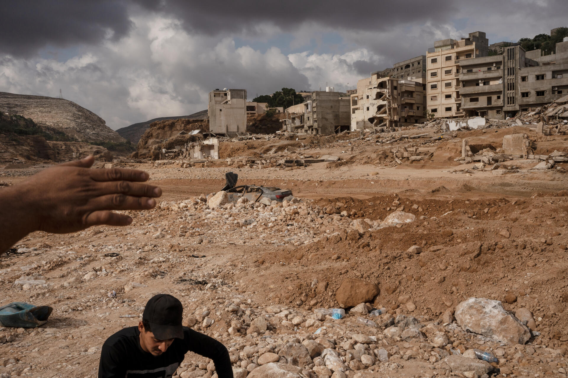Oussama, 20 ans, volontaire et habitant de la zone détruite, montre de la main les destructions, à Derna (Libye), le 19 septembre 2023.