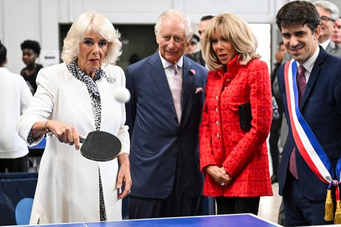 Britain's Queen Camilla plays table tennis as King Charles III, French President Emmanuel Macron's wife Brigitte Macron, and mayor of Saint-Denis Mathieu Hanotin, right, during a visit to a gymnasium, September 21, 2023 in Saint-Denis, outside Paris.