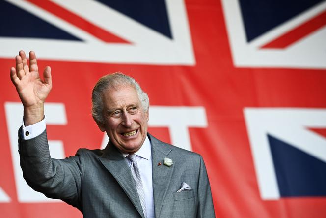 King Charles III waves to the crowd under a giant Union flag during a visit to a festival in celebration of British and French culture and business at Place de la Bourse in Bordeaux, southwestern France, on September 22, 2023.