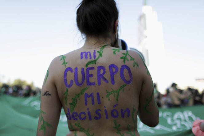 Una manifestante, cuyo cuerpo está pintado con la inscripción 