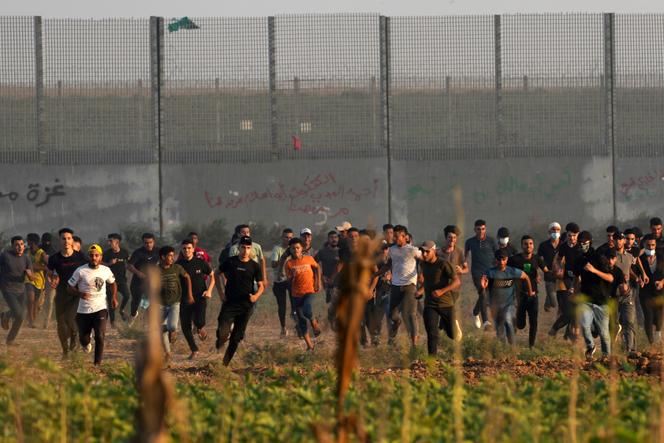 Palestinian protesters run to cover from teargas during clashes with Israeli security forces along the frontier with Israel, east of Gaza City, Friday, Sept. 22, 2023. The Israeli military said it struck three posts belonging to Hamas, the Islamic militant group that has controlled Gaza since 2007, following a number of incendiary balloons launched from Gaza into Israel. This is the latest violence to roil the territory as Palestinians stage routine protests by the border fence. (AP Photo/Adel Hana)