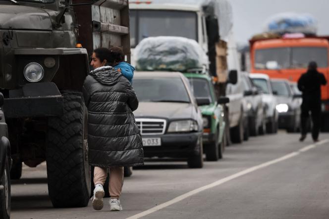 A refugee walks past a queue of vehicles waiting after crossing the border and arriving at a registration center of the Armenian foreign affairs ministry, near the border town of Kornidzor, on September 25, 2023.