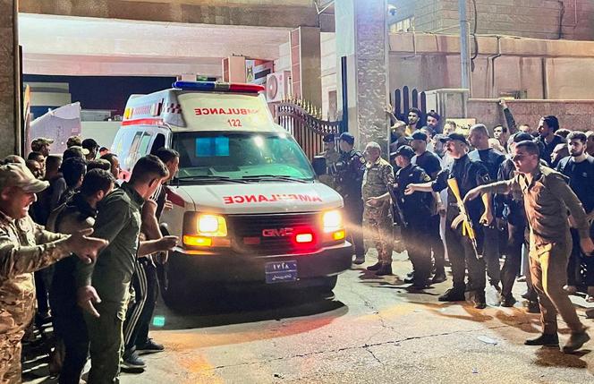 Security forces and emergency responders among others gather around ambulances carrying wounded people following a fatal fire at a wedding celebration, in the district of Hamdaniya in Iraq's Nineveh province, on September 27, 2023.