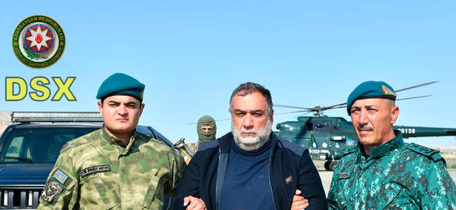 In this photo released by Azerbaijan's border guard service on Wednesday, Sept. 27, 2023, Azerbaijan's border guard officers pose with detained Ruben Vardanyan, center, in Nagorno-Karabakh.