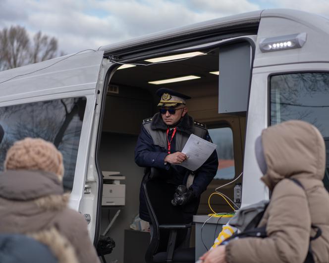 A policeman hands out papers for immigration applications at the Romanian emergency camp for Ukrainian refugees at the 9 May Stadium, Siret, February 28, 2022.