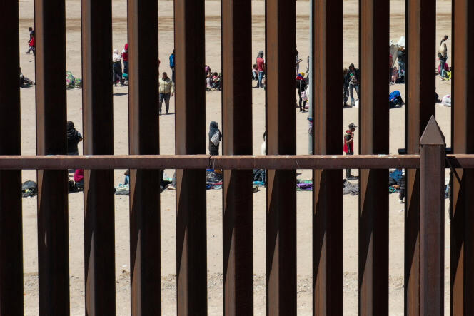 Migrantes esperan detrás de un muro en la frontera entre Estados Unidos y México, después de cruzar el Río Grande, el 11 de mayo de 2023. 