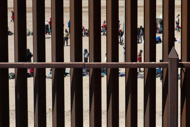 Des migrants patientent derrière un mur à la frontière entre les Etats-Unis et le Mexique, après avoir traversé le Rio Grande, le 11 mai 2023. 