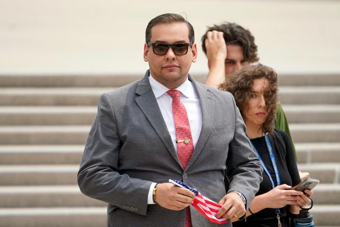 US republican lawmaker George Santos holds a miniature American flag that was presented to him as he departs federal court, June 30, 2023, in Central Islip, New York.