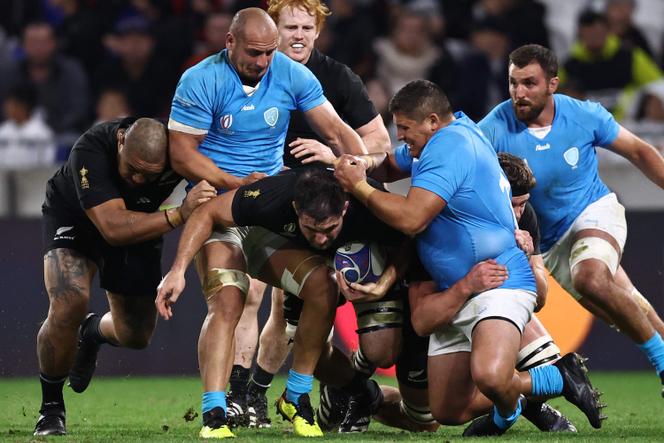New Zealand's number eight Luke Jacobson is tackled by Uruguay's prop Matias Benitez (R) and Uruguay's flanker Juan Manuel Rodríguez (L) during the France 2023 Rugby World Cup Pool A match between New Zealand and Uruguay at the OL Stadium in Decines-Charpieu, near Lyon, south-eastern France, on October 5, 2023.
