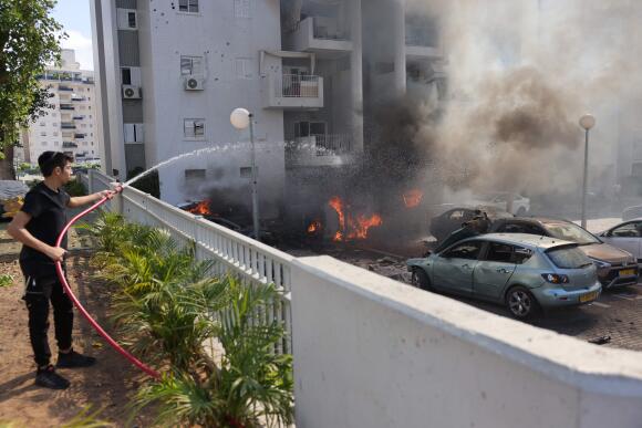 Un jeune Israélien éteint un incendie sur le parking d’un immeuble résidentiel à Ashkelon, le 7 octobre 2023.