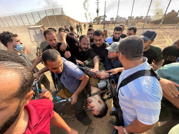 Des Palestiniens portent le corps d’une personne qu’ils disent être un Israélien tué par des hommes armés du Hamas qui ont infiltré des zones du sud d’Israël, le 7 octobre 2023.