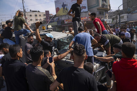 Des Palestiniens se rassemblent autour d’un véhicule de l’armée israélienne que des militants palestiniens ont conduit d’Israël à Gaza, à Shejaiya, dans la bande de Gaza, le 7 octobre 2023.