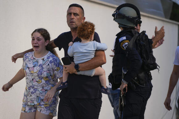 Des policiers israéliens évacuent une famille d’un site touché par une roquette tirée depuis la bande de Gaza, à Ashkelon, le 7 octobre 2023.