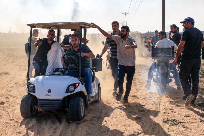 Palestinians transport a reportedly captured Israeli person, in Khan Yunis in the southern Gaza Strip, on October 7, 2023.