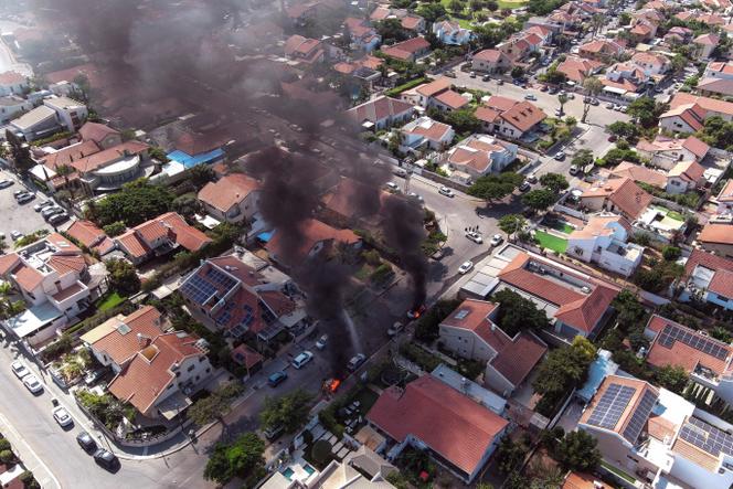 An aerial view shows vehicles on fire as rockets are launched from the Gaza Strip, in Ashkelon, southern Israel, on October 7, 2023.