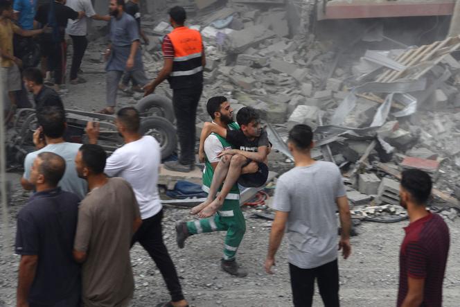 A Palestinian civil defense worker carries a boy rescued from the rubble of a house destroyed in an Israeli airstrike on Gaza City on October 9